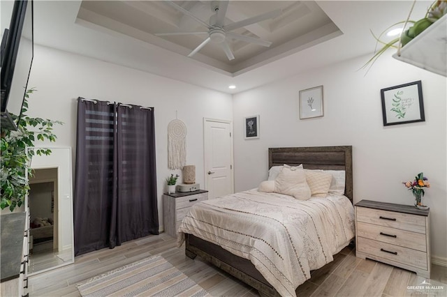 bedroom featuring light hardwood / wood-style floors, a raised ceiling, and ceiling fan