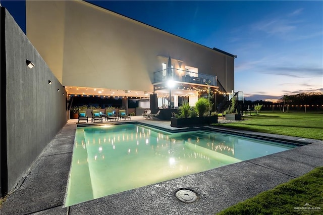 pool at dusk featuring a patio and a yard