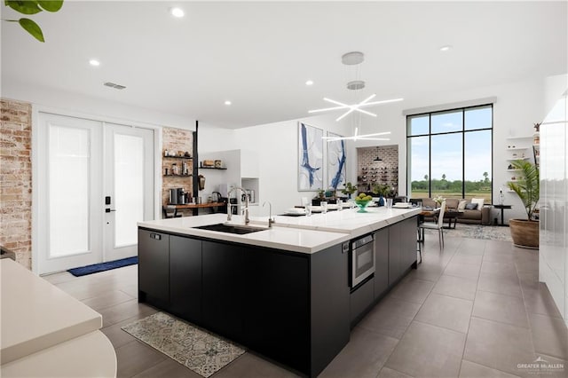 kitchen featuring a large island, brick wall, french doors, sink, and oven