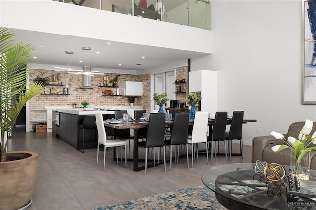 tiled dining space with brick wall and a towering ceiling