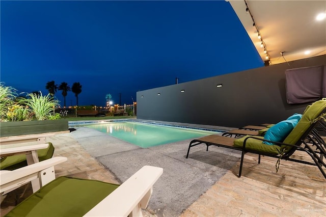 pool at twilight with a patio area