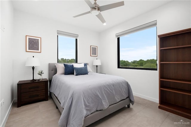 bedroom featuring ceiling fan, light tile patterned flooring, and multiple windows