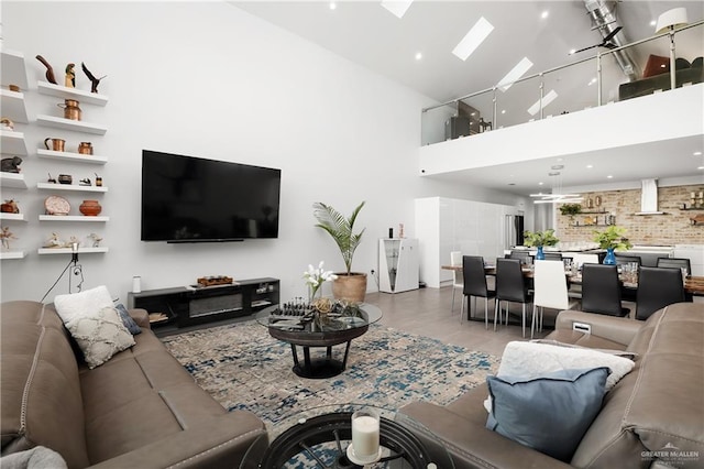 living room with light wood-type flooring, a skylight, and a towering ceiling