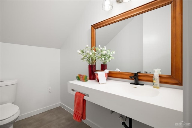 bathroom with sink, toilet, and lofted ceiling