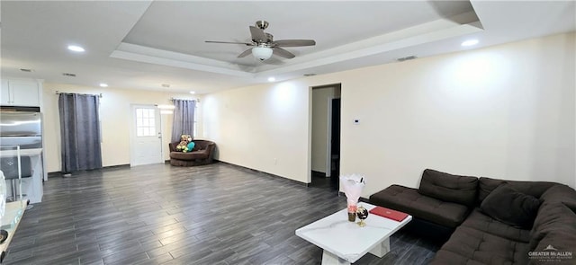 living area featuring a tray ceiling, recessed lighting, visible vents, dark wood-type flooring, and a ceiling fan