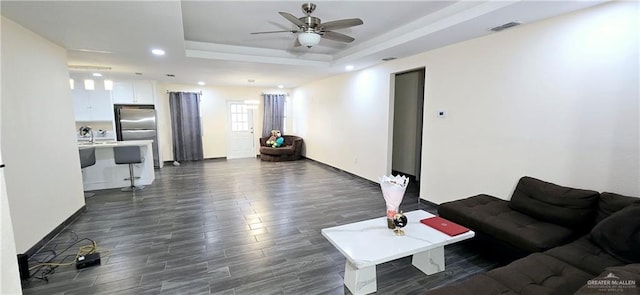 living area featuring visible vents, a raised ceiling, ceiling fan, dark wood-style flooring, and recessed lighting