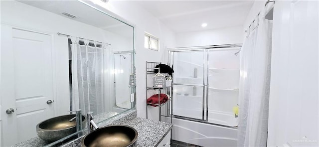 bathroom with enclosed tub / shower combo, visible vents, and vanity