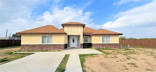 view of front of house with stone siding, fence, and stucco siding