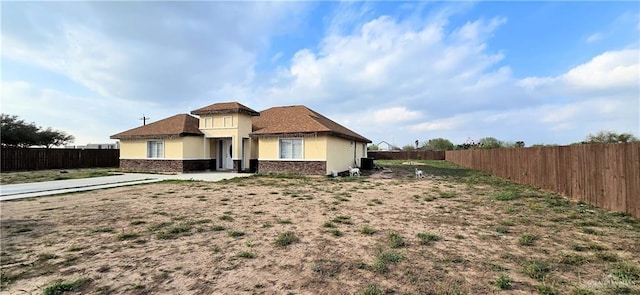 exterior space with brick siding, fence, and stucco siding