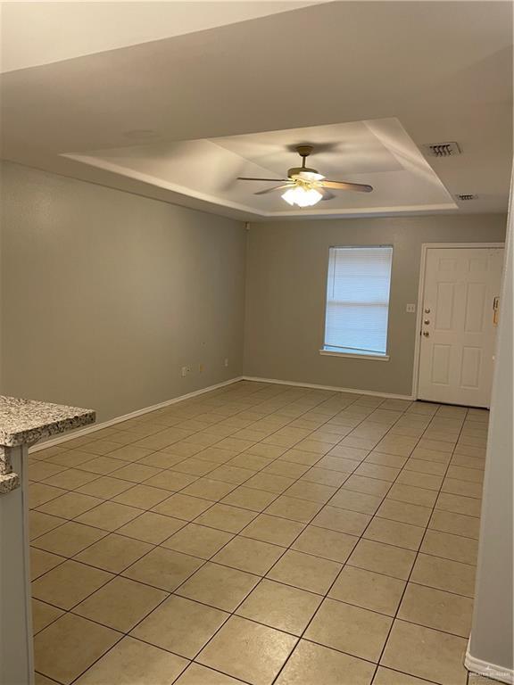 spare room with baseboards, a tray ceiling, visible vents, and a ceiling fan