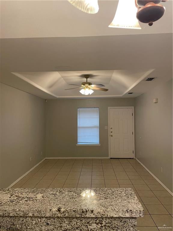 entrance foyer featuring ceiling fan, baseboards, a raised ceiling, and tile patterned floors