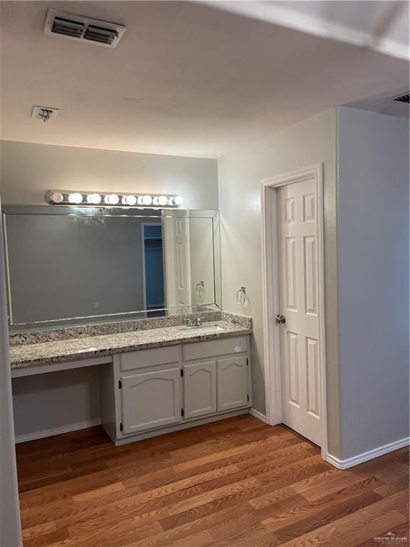 bathroom with baseboards, visible vents, wood finished floors, and vanity