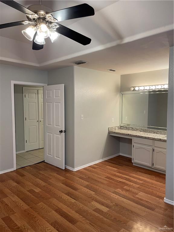 interior space featuring wood finished floors, built in study area, visible vents, and baseboards