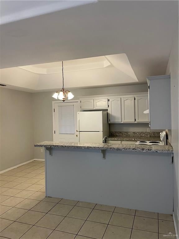 kitchen with white cabinets, a tray ceiling, freestanding refrigerator, and pendant lighting