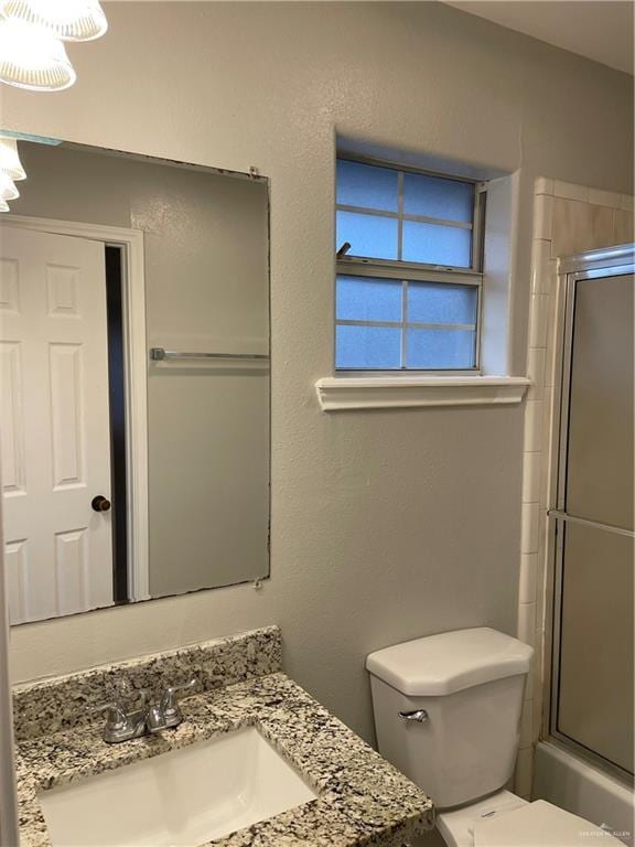 bathroom featuring toilet, combined bath / shower with glass door, and vanity