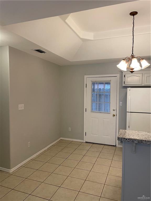 entryway with light tile patterned floors, lofted ceiling, visible vents, a chandelier, and baseboards