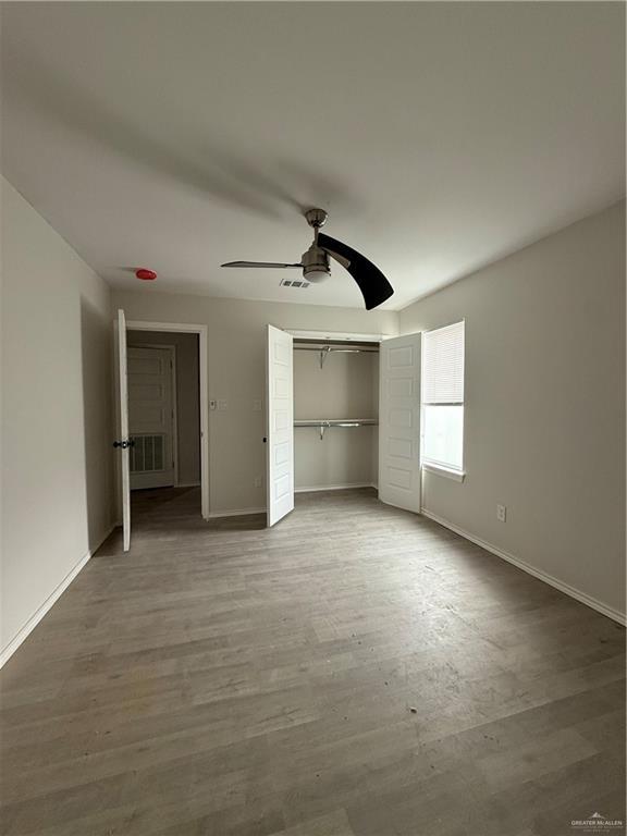 unfurnished bedroom with ceiling fan, wood-type flooring, and a closet