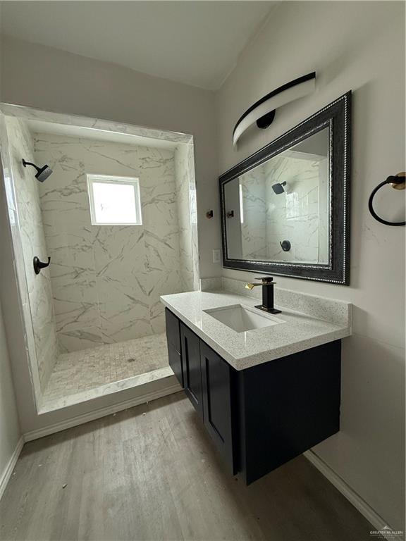 bathroom with a tile shower, vanity, and hardwood / wood-style flooring