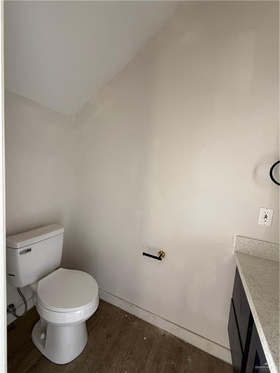 bathroom with vanity, hardwood / wood-style flooring, toilet, and vaulted ceiling