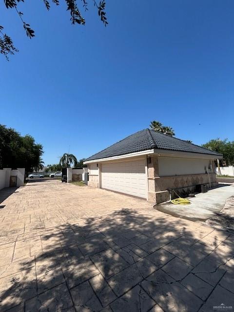 2417 E 28th St, Mission, TX 78574 - view of property exterior featuring a garage, a tile roof, and driveway