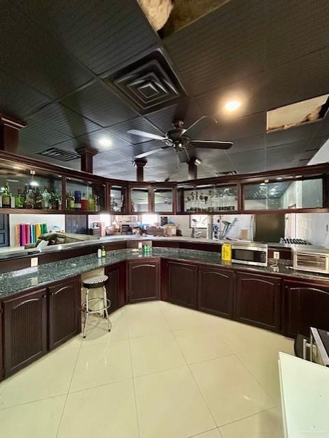2417 E 28th St, Mission, TX 78574 - kitchen featuring light tile patterned flooring, a ceiling fan, stainless steel microwave, dark countertops, and dark brown cabinets
