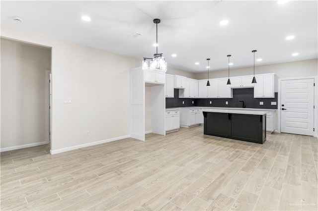 kitchen with light wood-type flooring, backsplash, pendant lighting, white cabinets, and a kitchen island