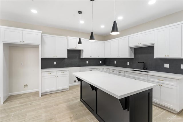 kitchen with sink, a kitchen island, backsplash, decorative light fixtures, and white cabinets