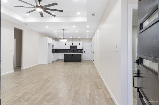 kitchen with ceiling fan, a center island, hanging light fixtures, light hardwood / wood-style flooring, and white cabinets