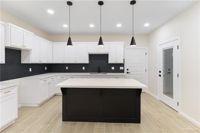 kitchen with decorative light fixtures, a center island, white cabinetry, and sink