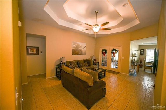 living room featuring ceiling fan, a raised ceiling, light tile patterned floors, and french doors