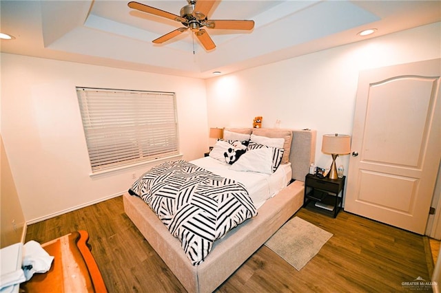 bedroom featuring ceiling fan, a raised ceiling, and dark wood-type flooring