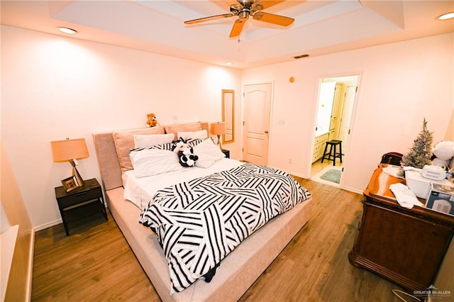 bedroom featuring wood-type flooring, a raised ceiling, and ceiling fan