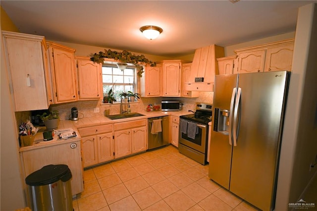 kitchen featuring light brown cabinets, backsplash, sink, light tile patterned floors, and stainless steel appliances