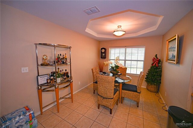 dining room with a tray ceiling and light tile patterned floors