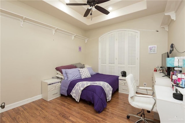 bedroom featuring ceiling fan, dark hardwood / wood-style floors, and a raised ceiling