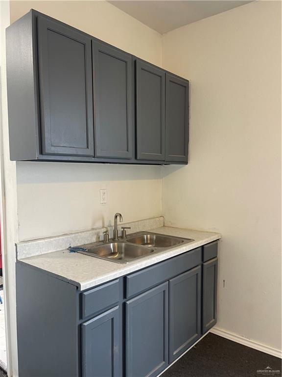 kitchen featuring a sink, baseboards, gray cabinets, and light countertops