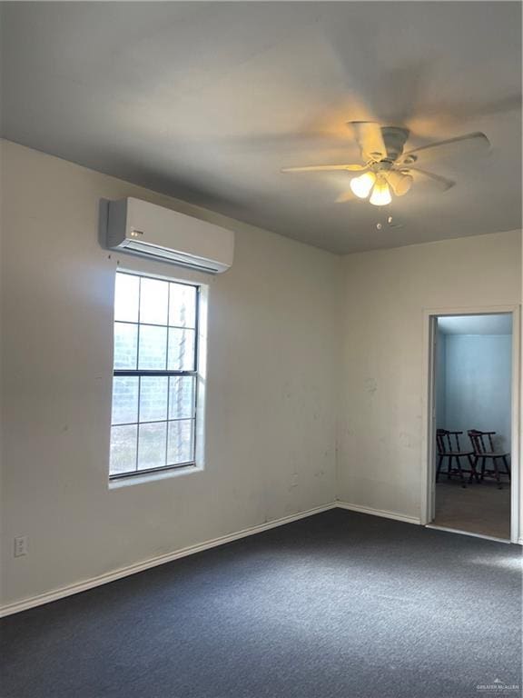 spare room with a wall mounted air conditioner, carpet flooring, a ceiling fan, and baseboards