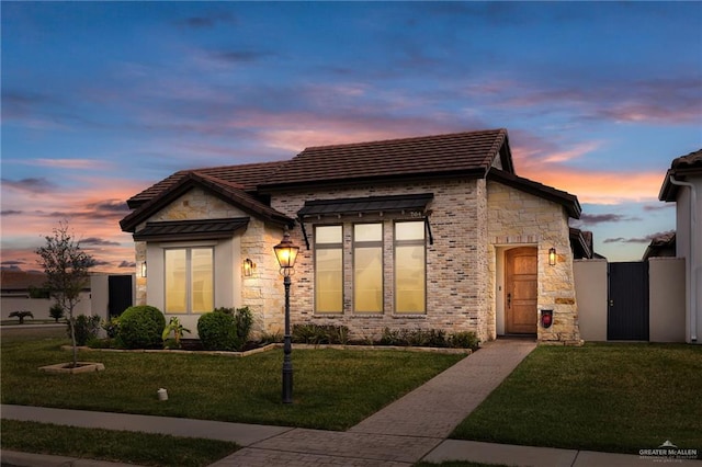 view of front of property featuring stone siding, a front yard, and a gate