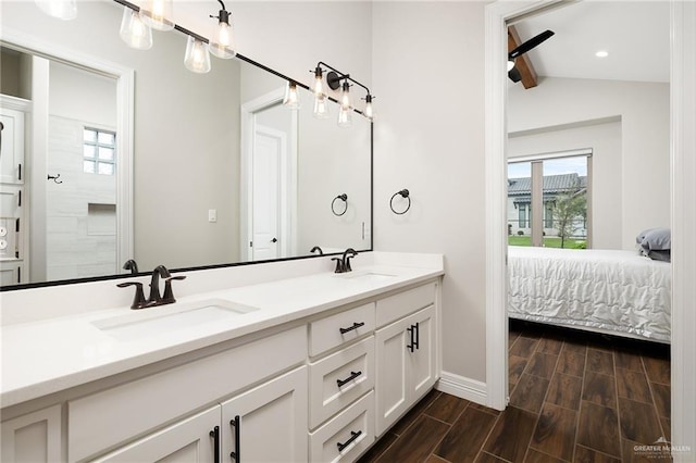 full bathroom featuring a sink, wood finish floors, double vanity, and vaulted ceiling