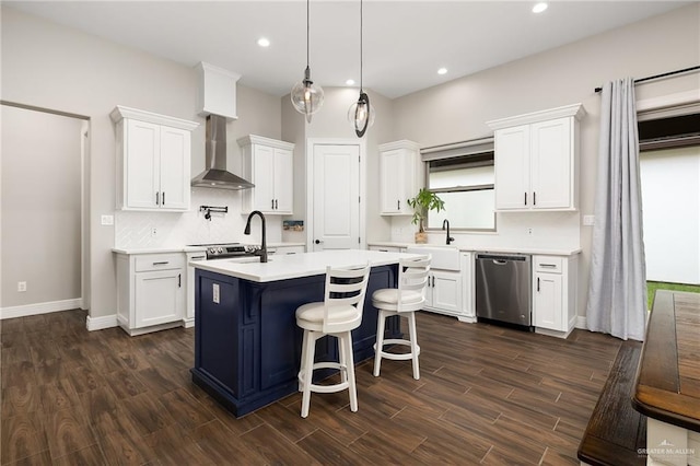 kitchen featuring wall chimney range hood, dishwasher, light countertops, white cabinetry, and a kitchen island with sink