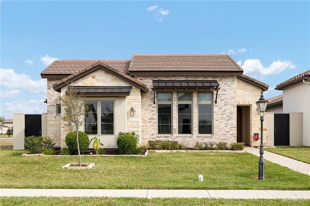 view of front of house featuring a front lawn, a tile roof, and stone siding