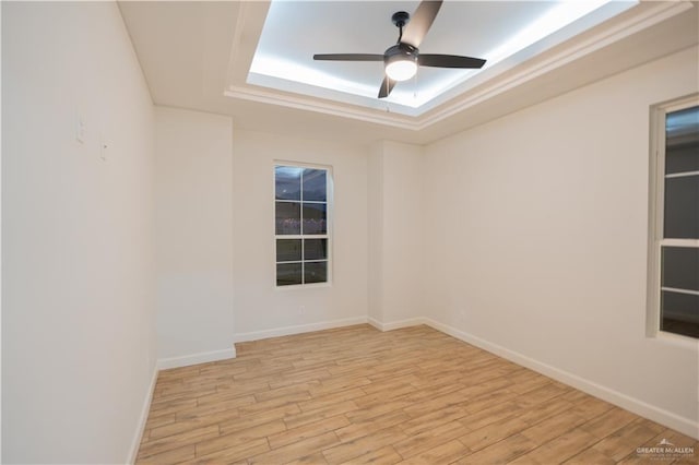 spare room featuring ceiling fan, a raised ceiling, and light wood-type flooring