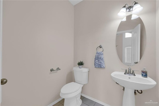 bathroom with toilet, baseboards, and tile patterned flooring