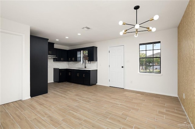 kitchen featuring light countertops, visible vents, backsplash, an inviting chandelier, and dark cabinets