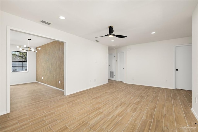 unfurnished room featuring ceiling fan with notable chandelier, light wood-type flooring, visible vents, and recessed lighting