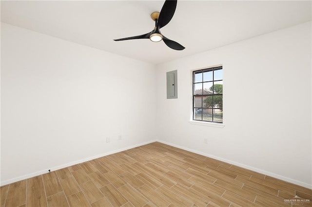 empty room featuring light wood-style flooring, electric panel, baseboards, and a ceiling fan