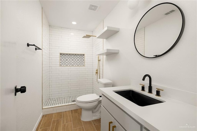 bathroom with wood tiled floor, visible vents, a tile shower, and toilet