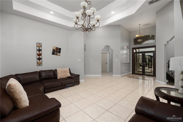 tiled living room featuring a raised ceiling, a towering ceiling, and an inviting chandelier