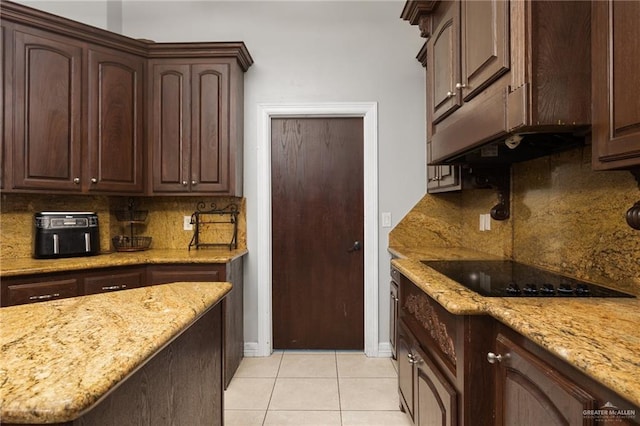 kitchen featuring tasteful backsplash, black electric cooktop, dark brown cabinets, and light tile patterned flooring