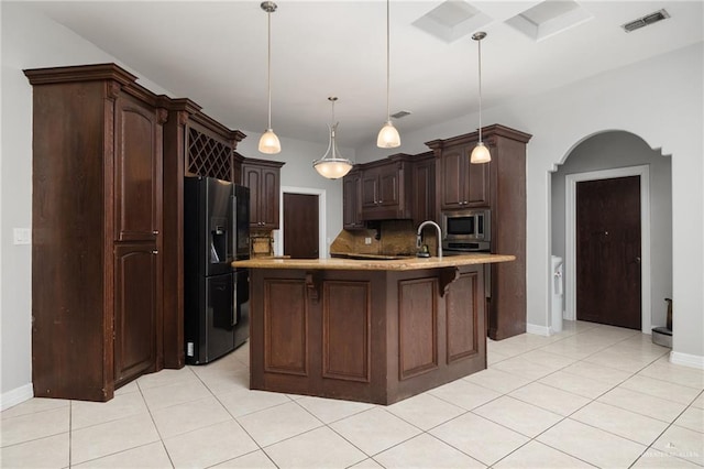 kitchen with stainless steel microwave, hanging light fixtures, tasteful backsplash, black fridge with ice dispenser, and dark brown cabinetry